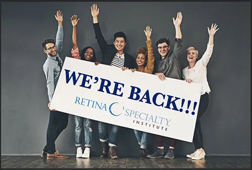 Group of people holding a We're Back sign