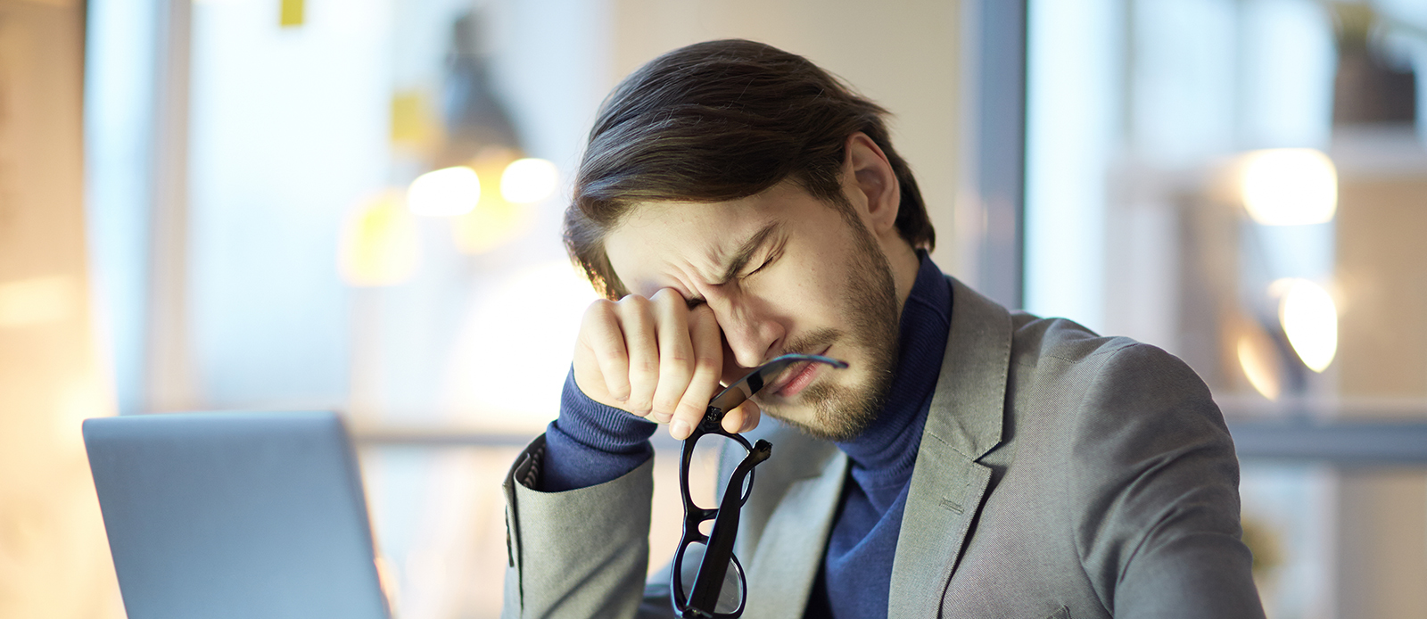 young businessman rubbing his eyes