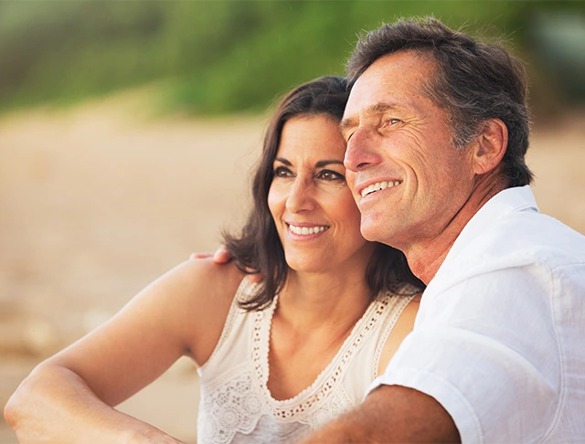 Mature happy couple sitting on the beach