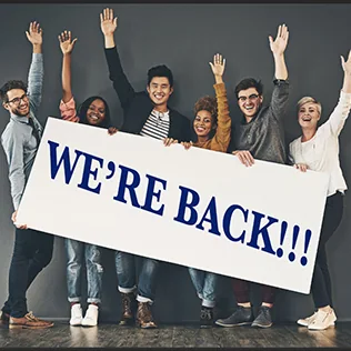 Group of workers holding a sign that reads, "We're Back!"