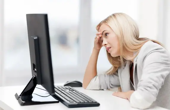 Woman looking at computer screen with hand to her head