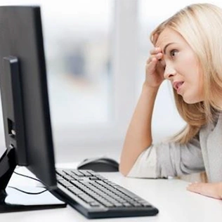 Woman looking at computer screen with hand to her head